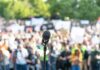 Microphone on a stand facing a large blurred crowd