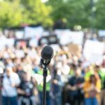 Microphone on a stand facing a large blurred crowd