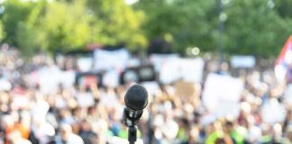 Microphone on a stand facing a large blurred crowd