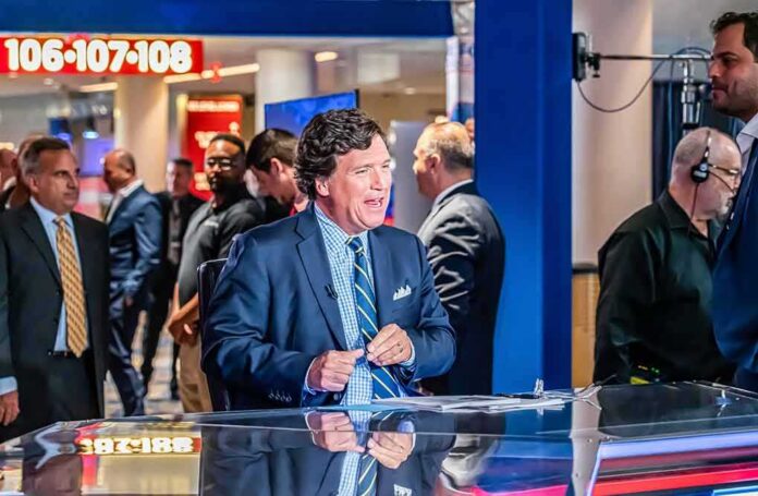 news anchor at a studio desk with crew and onlookers