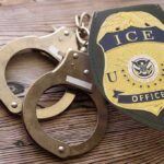 ICE officer badge and handcuffs on wooden surface