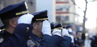 uniformed police officers salute in formation outdoors