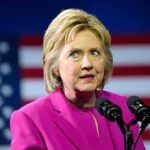 woman in pink blazer speaking at microphones