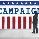 Man in suit writing on large campaign banner with stars and stripes