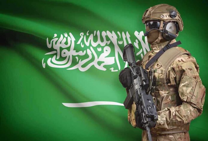 shutterstock_514924306 Soldier in tactical gear stands before a green flag