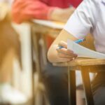 student filling out exam sheet at a desk