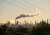 Trump’s Pause Shattered – Wallets on Deck Industrial refinery with smokestack emitting plume at sunset