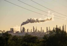 Trump’s Pause Shattered – Wallets on Deck Industrial refinery with smokestack emitting plume at sunset