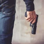 person holding a handgun by their side