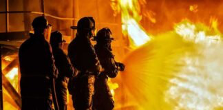 Firefighters battling a large blaze with a hose