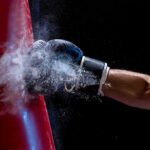 Boxer’s gloved fist strikes a red punching bag, sending chalk dust into the air