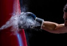 Boxer’s gloved fist strikes a red punching bag, sending chalk dust into the air