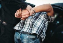 Millions of Leads Led to Just Eight Arrests police officer handcuffing person against a car