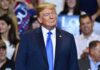 Nuclear Ultimatum: Trump Stares Down Iran Donald Trump at a rally wearing a dark suit and blue tie