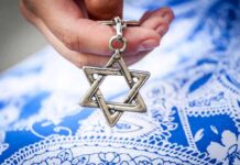 Hand holding a metal Star of David pendant