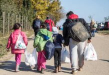 Group of people walking along a road carrying bags