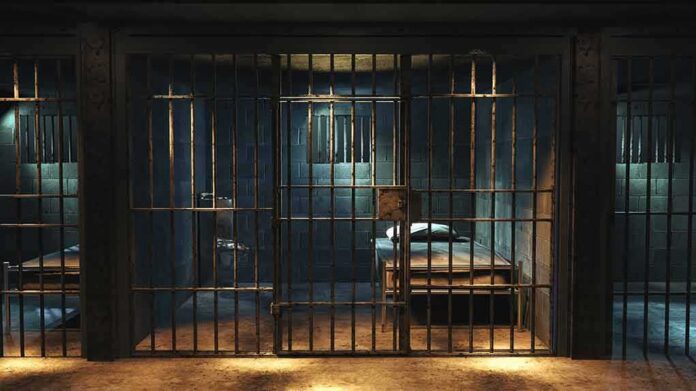 Prison cell with metal bars and a single bed