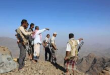 Group of armed men standing on a rocky mountain ridge