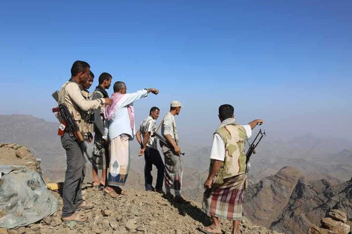 Group of armed men standing on a rocky mountain ridge
