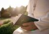 Person in white robe holding a Bible outdoors