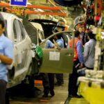 Teddy Williams on an automotive assembly line with workers fitting car doors