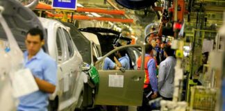 Teddy Williams on an automotive assembly line with workers fitting car doors