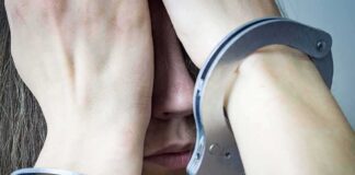 Person in handcuffs covering face with hands