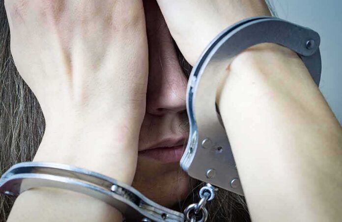 Person in handcuffs covering face with hands