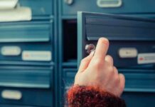 A hand holding a key, opening a blue mailbox drawer