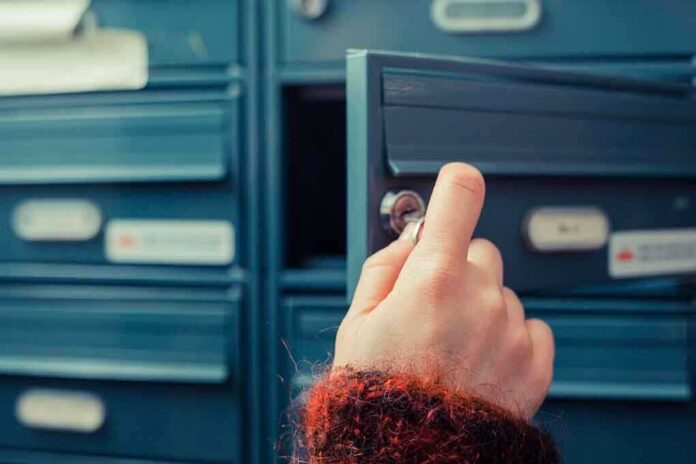 A hand holding a key, opening a blue mailbox drawer