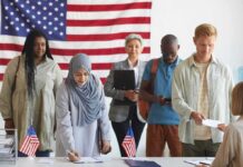 Citizenship? California Shrugs, DOJ Strikes Voters standing in line at a polling station with a U.S. flag