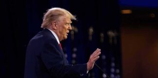 Donald Trump speaking at a podium with hand raised