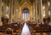 Interior of a grand cathedral with seated visitors facing the altar