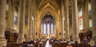 Interior of a grand cathedral with seated visitors facing the altar