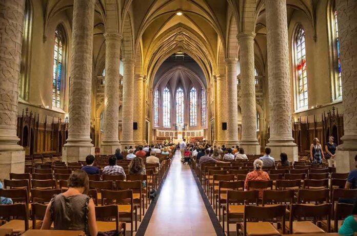 Interior of a grand cathedral with seated visitors facing the altar