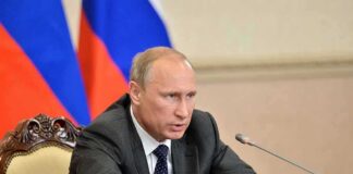 Vladimir Putin speaking at a meeting with documents and a microphone