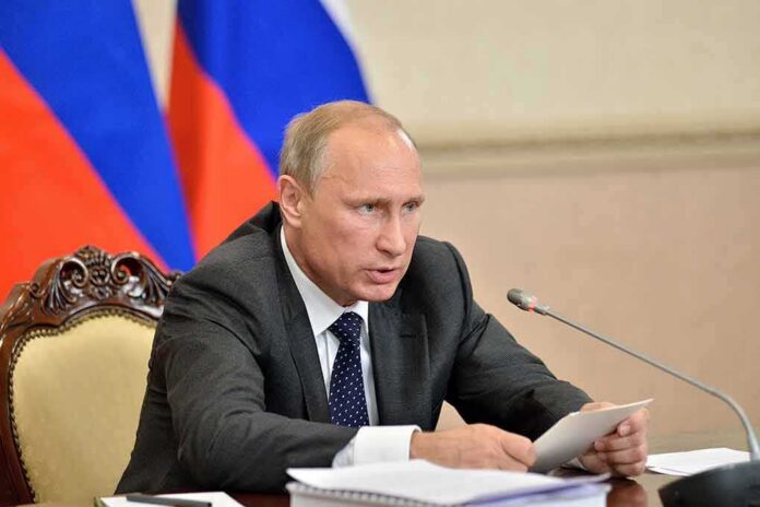 Vladimir Putin speaking at a meeting with documents and a microphone