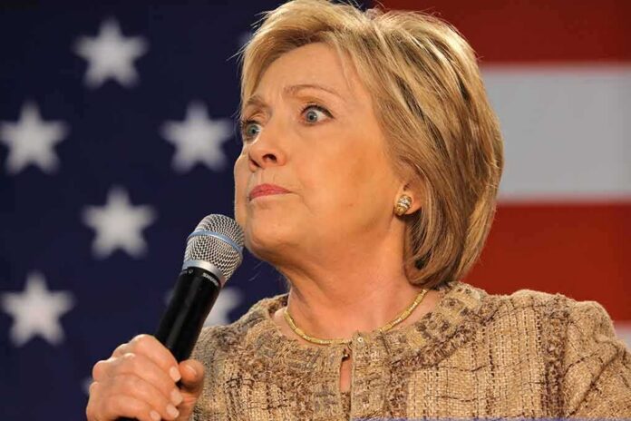 Hilary Cawthorne speaking into a microphone against a U.S. flag backdrop