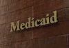 A Leaked Report, a Courtroom Twist, and Millions Medicaid sign on a brown wooden wall