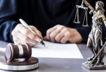 Prosecutions As Warning Shot? Senator Sparks Fury Judge writing at desk with gavel and Lady Justice statue